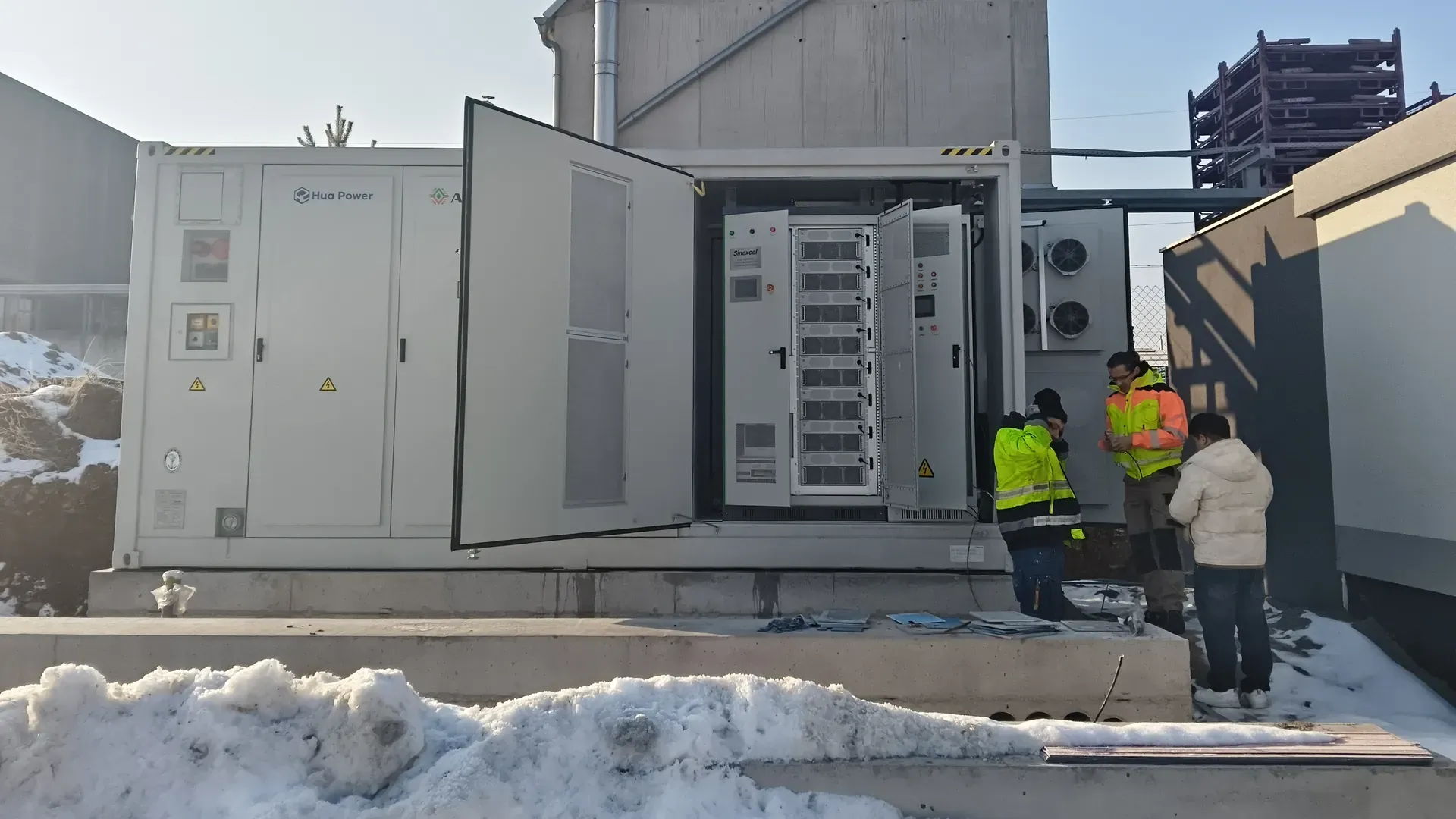 Hua Power liquid-cooled battery storage container with its doors open on site, with engineers inspecting the cabinet interior