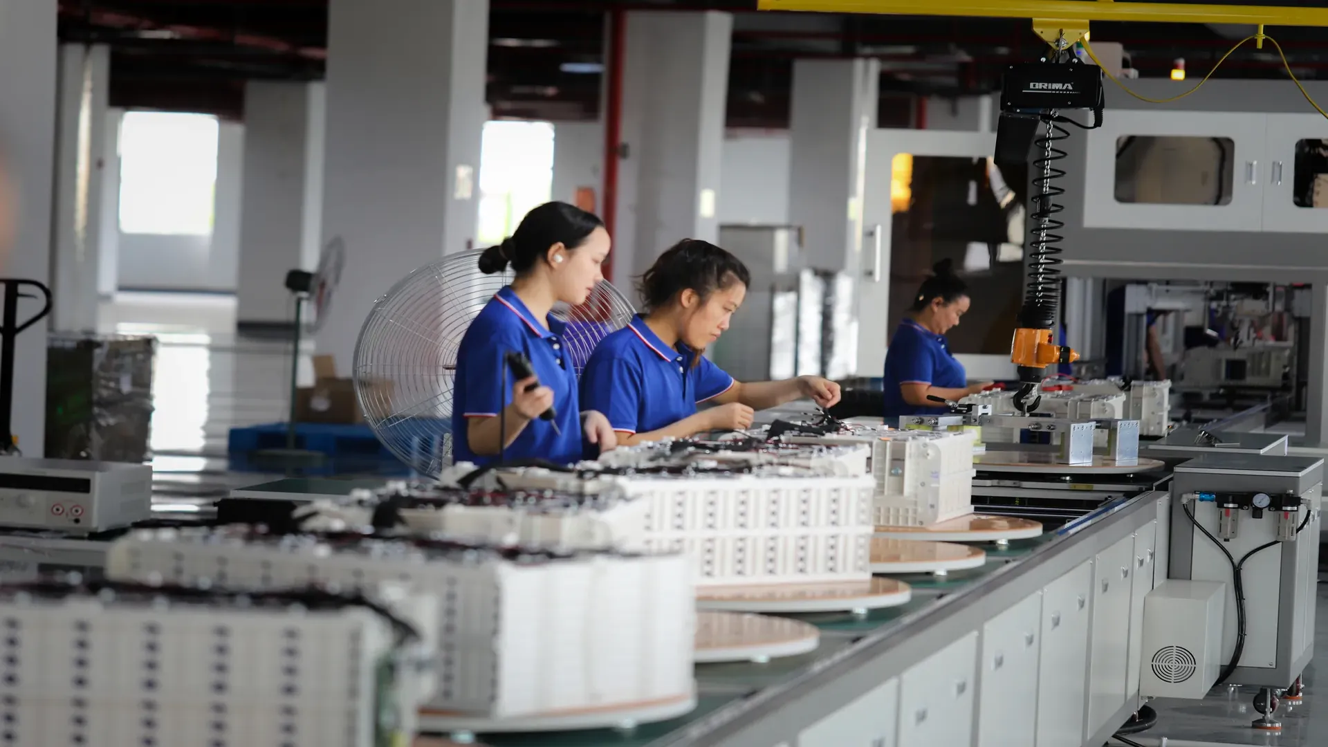 Technicians assembling lithium battery modules on a storage manufacturing line in a clean workshop